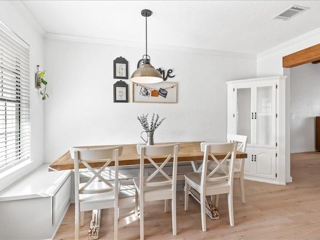 dining space with breakfast area, visible vents, light wood-style floors, and crown molding