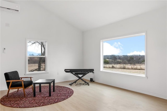 sitting room featuring wood finished floors, vaulted ceiling, and a wall mounted AC