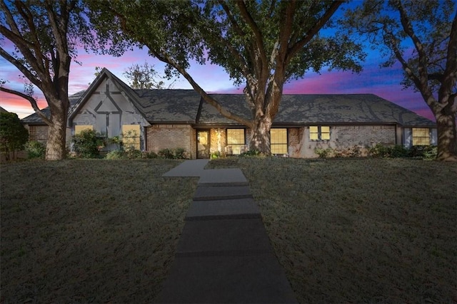 view of front of home featuring brick siding and a yard