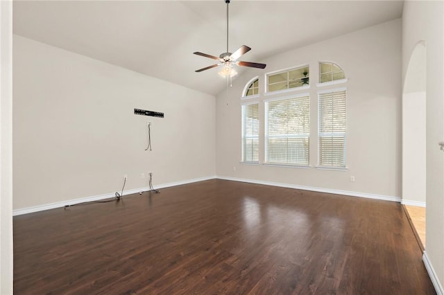 empty room featuring a ceiling fan, vaulted ceiling, dark wood-style floors, and baseboards