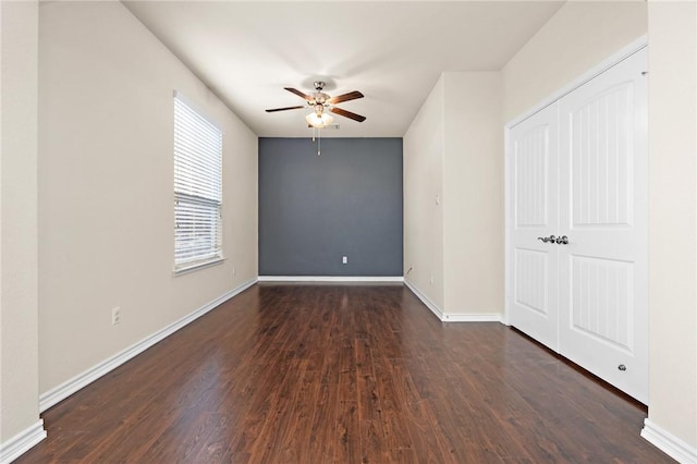 empty room with a ceiling fan, dark wood-style flooring, and baseboards