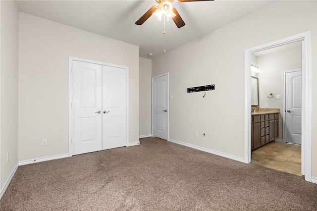 unfurnished bedroom with a closet, light colored carpet, connected bathroom, and baseboards