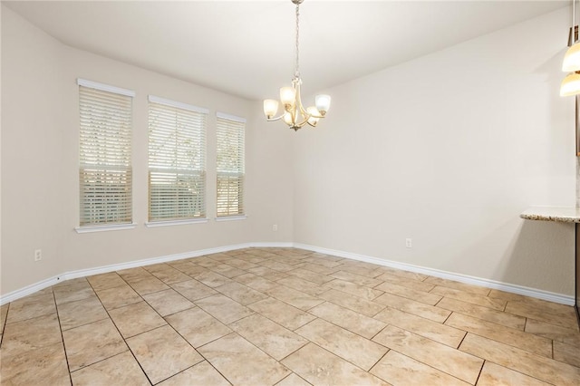 unfurnished room with baseboards and a chandelier