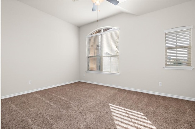 empty room featuring lofted ceiling, carpet flooring, a ceiling fan, and baseboards