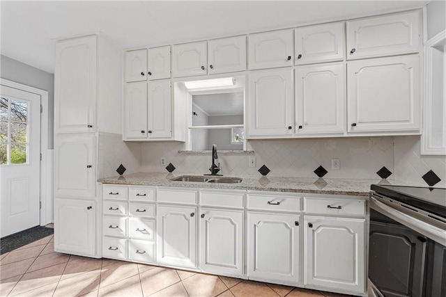 kitchen featuring a sink, stainless steel electric stove, light tile patterned flooring, and white cabinetry