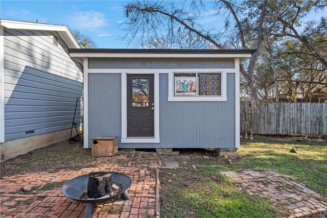 view of outbuilding with an outbuilding, an outdoor fire pit, and fence