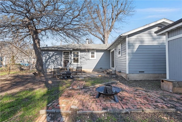 rear view of property featuring crawl space, an outdoor fire pit, and a patio