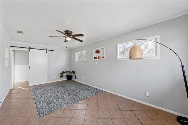empty room featuring visible vents, ornamental molding, tile patterned flooring, ceiling fan, and a barn door