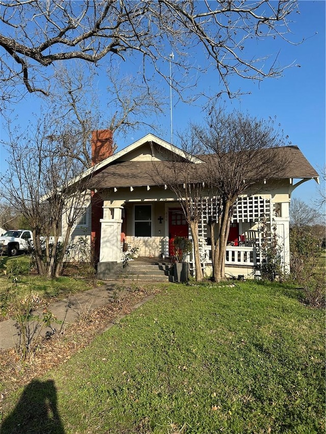 view of front of house with a porch, a chimney, and a front lawn
