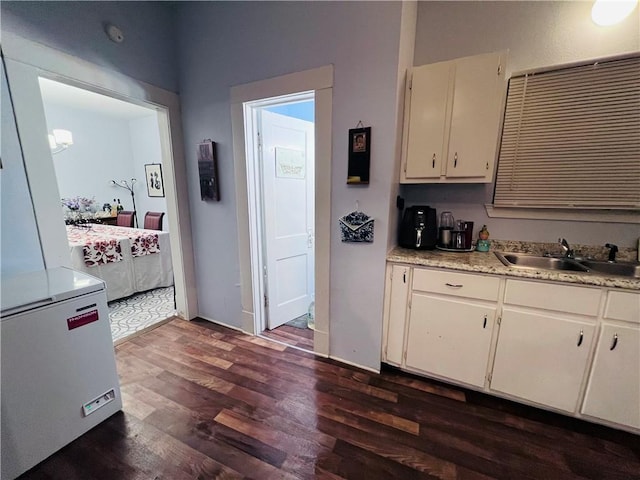 kitchen with light countertops, white cabinets, dark wood-style floors, and a sink