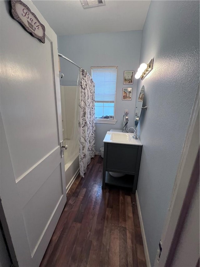 full bath featuring vanity, wood finished floors, baseboards, shower / bath combo with shower curtain, and toilet