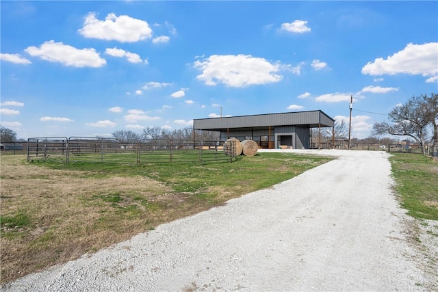 view of front of property with an exterior structure, a detached garage, driveway, a rural view, and an outdoor structure