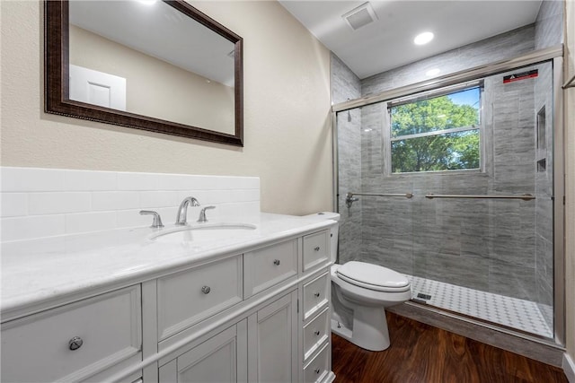bathroom featuring a stall shower, toilet, wood finished floors, and vanity