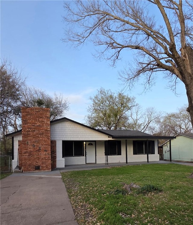 view of front of house featuring driveway, a chimney, and a front lawn