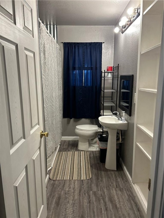 202 Coryell City Rd, Gatesville, TX 76528 - bathroom featuring a shower with curtain, wood finished floors, baseboards, toilet, and a textured wall