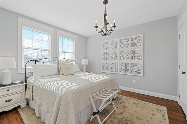 bedroom with a notable chandelier, wood finished floors, and baseboards