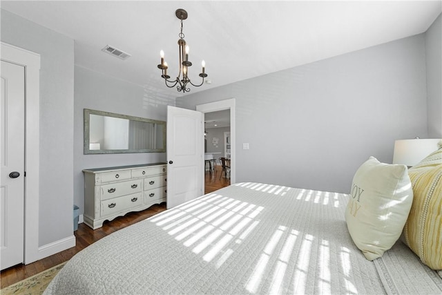 bedroom featuring visible vents, wood finished floors, baseboards, and a chandelier