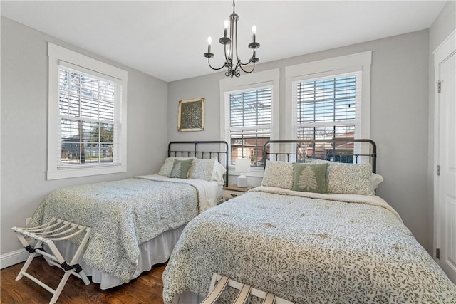 bedroom featuring dark wood-type flooring, multiple windows, a notable chandelier, and baseboards