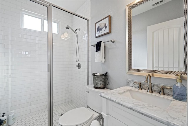 full bathroom with vanity, a shower stall, toilet, and visible vents