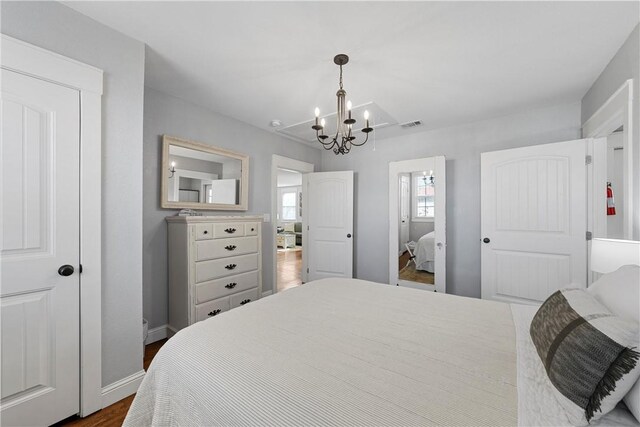 bedroom with visible vents, baseboards, a notable chandelier, and dark wood finished floors