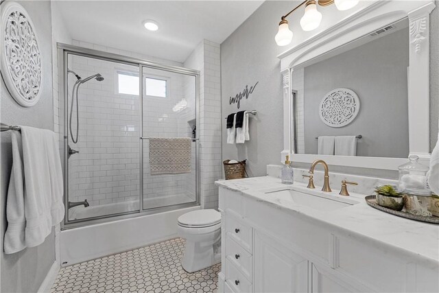 full bathroom featuring visible vents, toilet, tile patterned floors, combined bath / shower with glass door, and vanity