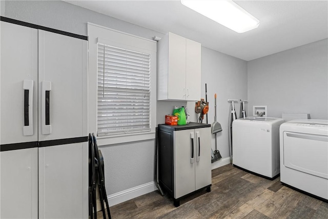 washroom with baseboards, cabinet space, washing machine and dryer, and dark wood-style flooring