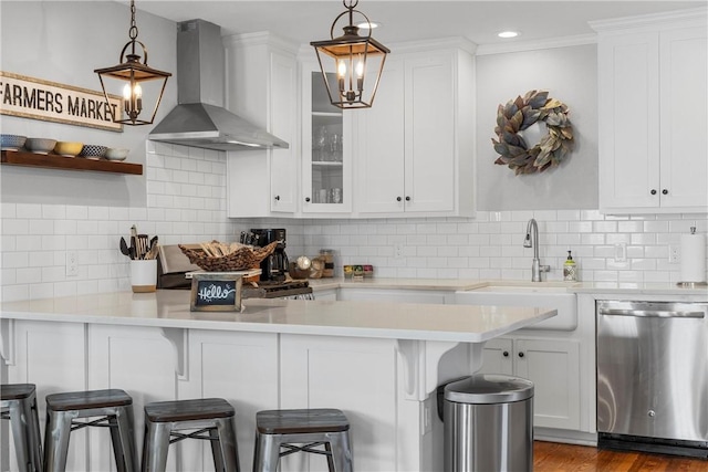 kitchen featuring a breakfast bar, stainless steel dishwasher, white cabinetry, wall chimney exhaust hood, and light countertops