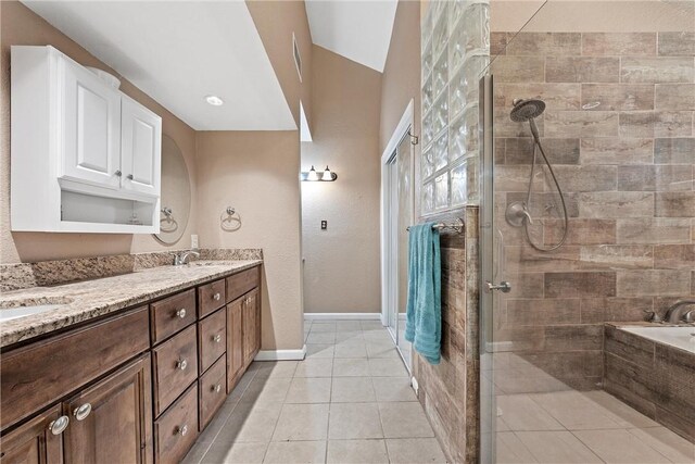 bathroom with a tile shower, a sink, tile patterned floors, and double vanity