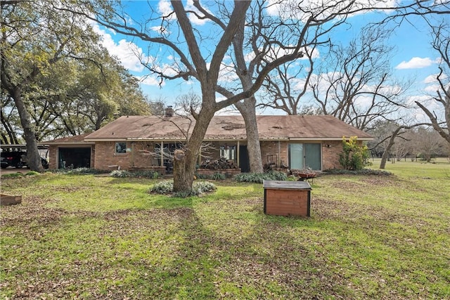 rear view of house featuring a yard, brick siding, and an attached garage