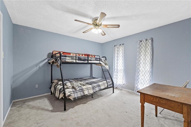 carpeted bedroom featuring baseboards, a textured ceiling, and ceiling fan