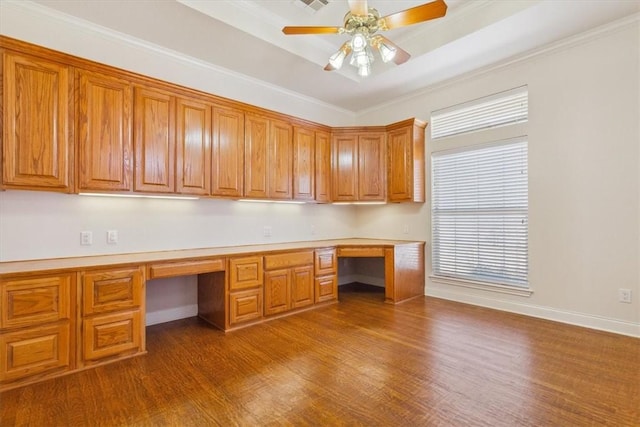 unfurnished office featuring dark wood finished floors, ceiling fan, baseboards, and built in study area