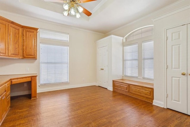 unfurnished office featuring ornamental molding, a tray ceiling, ceiling fan, and wood finished floors