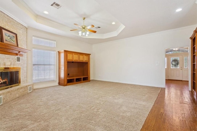 unfurnished living room with visible vents, crown molding, a raised ceiling, and a ceiling fan