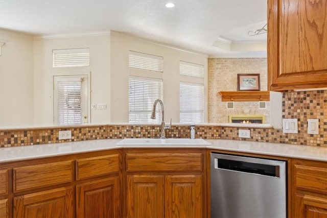 kitchen featuring crown molding, dishwasher, light countertops, brown cabinetry, and a sink
