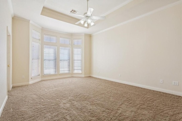 carpeted empty room with visible vents, baseboards, a tray ceiling, and ornamental molding