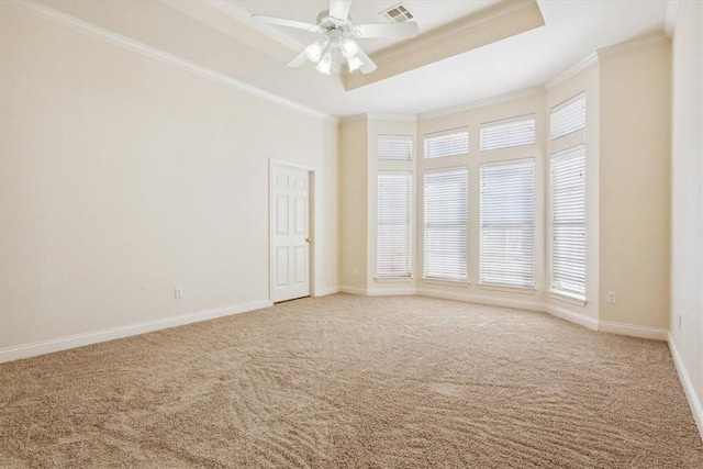 carpeted spare room with visible vents, a healthy amount of sunlight, crown molding, and a raised ceiling