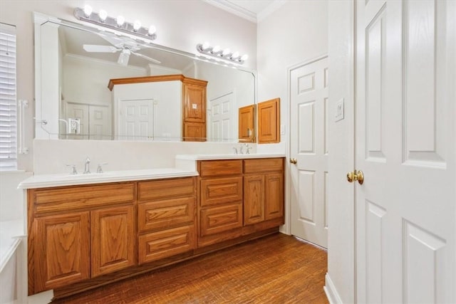 full bath featuring crown molding, wood finished floors, double vanity, and a sink