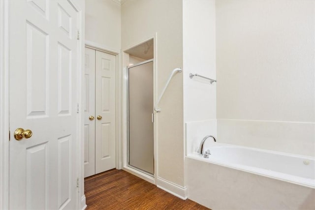full bath featuring a bath, a shower stall, and wood finished floors