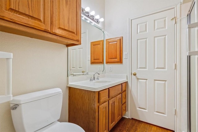 bathroom featuring toilet, vanity, and wood finished floors