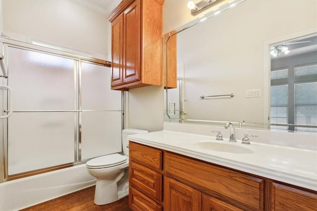 full bathroom with vanity, toilet, wood finished floors, and bath / shower combo with glass door