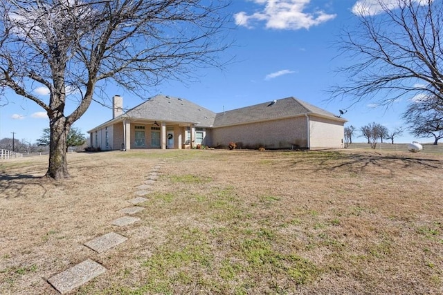 back of house featuring a lawn and a chimney