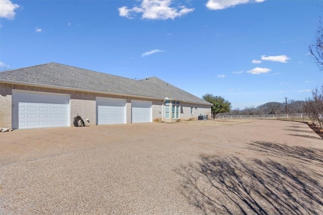 exterior space with brick siding, an attached garage, driveway, and fence