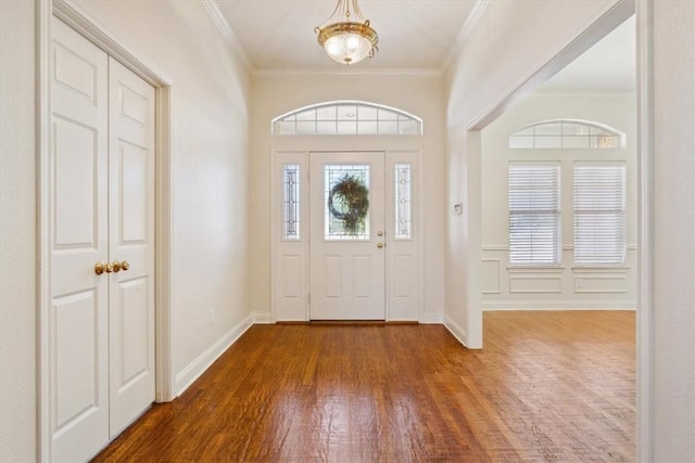 entryway featuring crown molding, a notable chandelier, wood finished floors, and baseboards