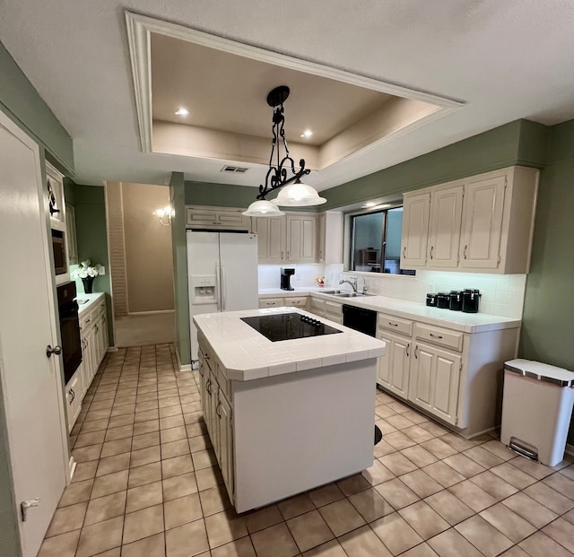 1016 Cardinal Dr, Woodway, TX 76712 - kitchen with a raised ceiling, black appliances, light tile patterned floors, a kitchen island, and a sink