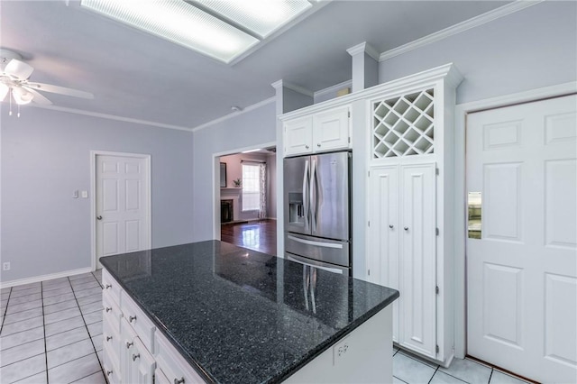 kitchen with stainless steel refrigerator with ice dispenser, white cabinets, crown molding, light tile patterned floors, and ceiling fan
