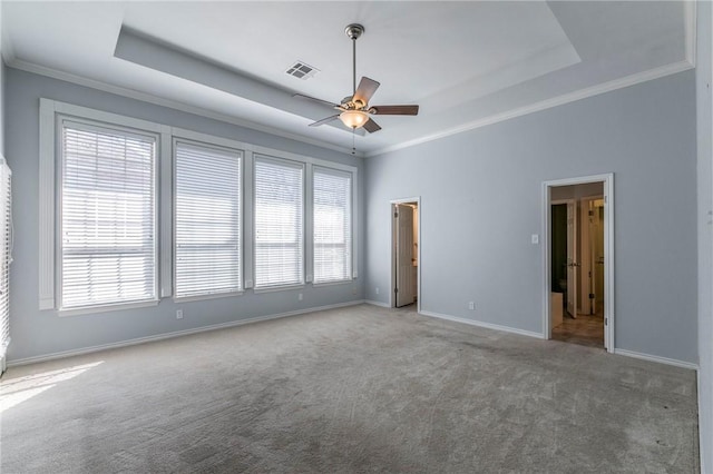 empty room featuring visible vents, ornamental molding, a ceiling fan, a tray ceiling, and baseboards
