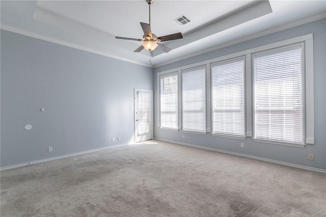carpeted empty room with a raised ceiling, baseboards, visible vents, and ceiling fan