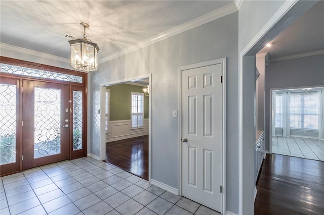 foyer entrance with a chandelier, tile patterned flooring, and crown molding