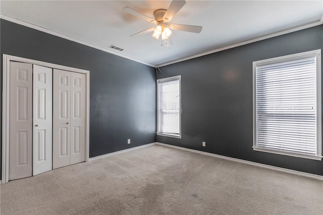 unfurnished bedroom with visible vents, carpet floors, a closet, and ornamental molding