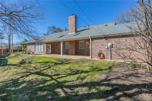 rear view of house featuring fence, a patio area, a lawn, and a chimney